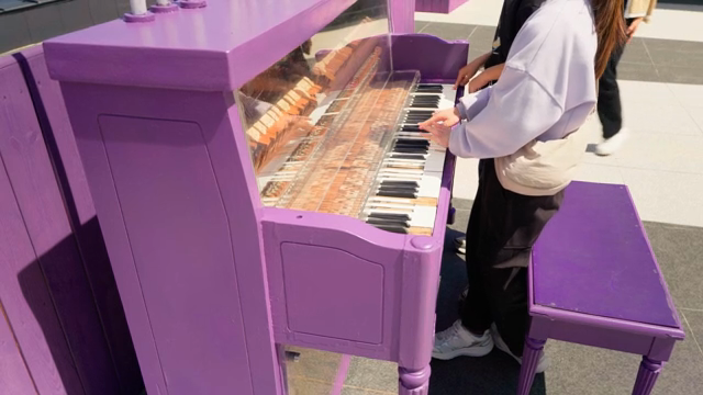 A person playing a purple piano outdoors