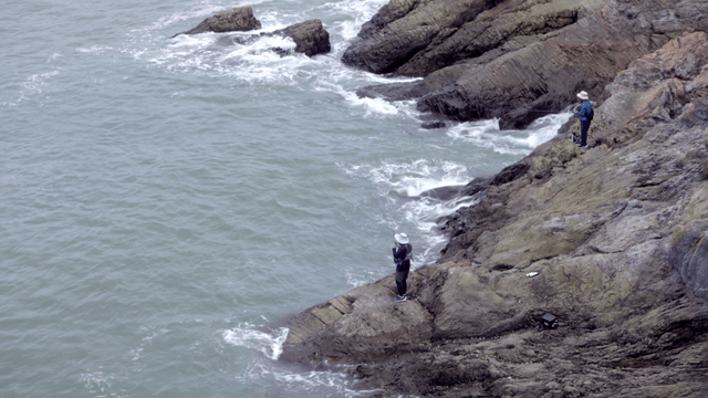바위 해안에서 낚시하는 두 사람