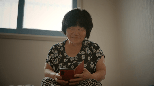 An elderly woman using a smartphone indoors
