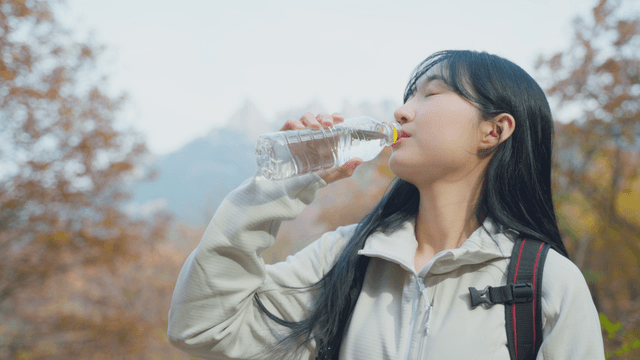 Woman drinking water in autumn hillside