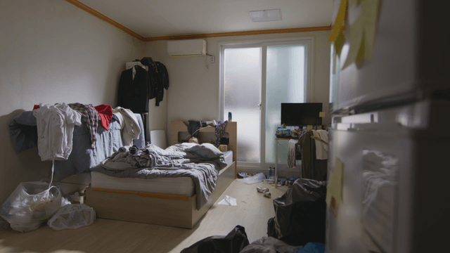 Person lying in a messy room with clothes and garbage