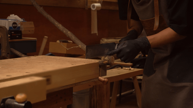 Artisan practicing wood cutting with a saw in workshop