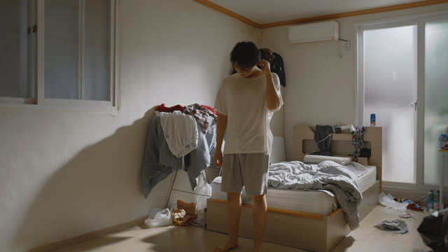 Man standing in a messy bedroom
