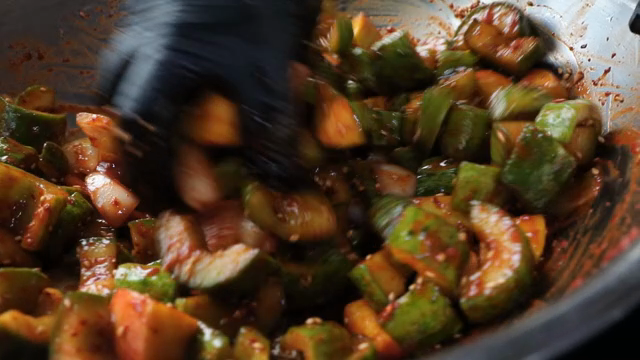 Mixing cucumber kimchi in a metal bowl