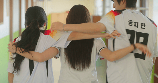 Three friends in sports uniforms with arms around each other