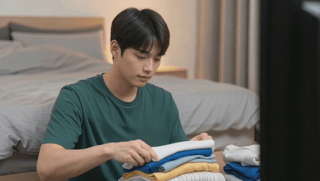 티비 보며 침실에서 옷을 개는 남자