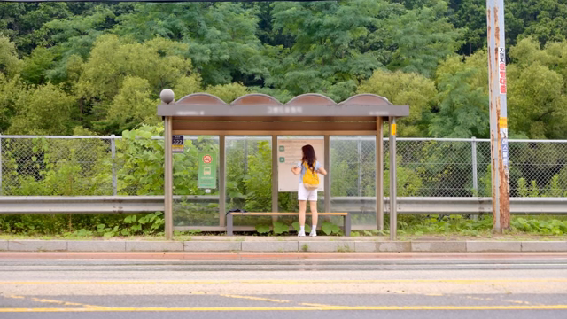 시골의 버스 정류장에서 기다리는 여성