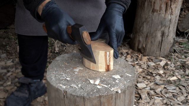 Person chopping wood with an axe outdoors
