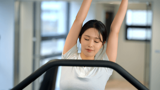 Woman stretching on a treadmill at gym