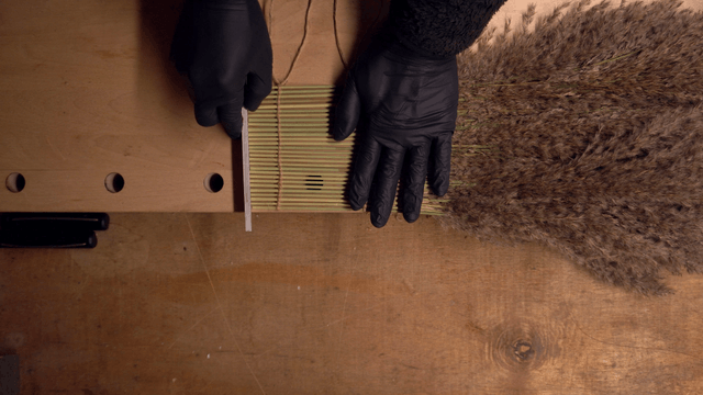 Hand arranging dried reeds on a table