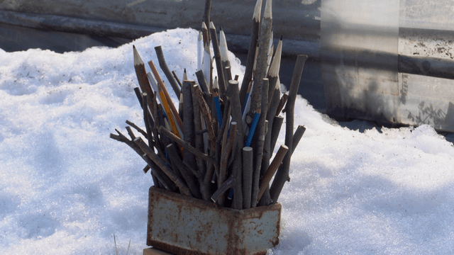 Wooden pencil sculpture placed on snow-covered ground