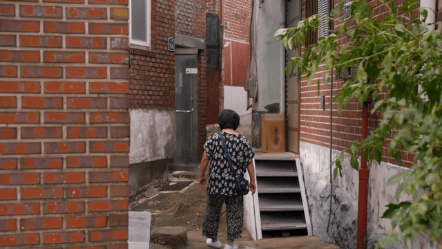 An elderly woman walking in an alley