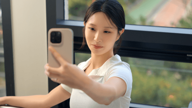 Young woman taking a selfie by the window