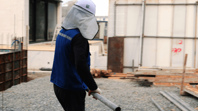 Worker carrying a metal pipe at a construction site