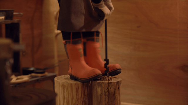 Person drilling into a wooden log indoors