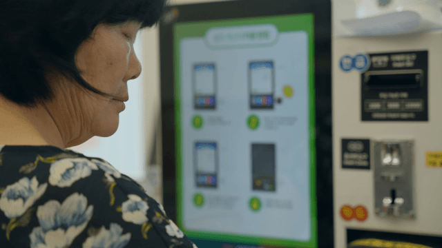 An elderly woman using a digital kiosk indoors