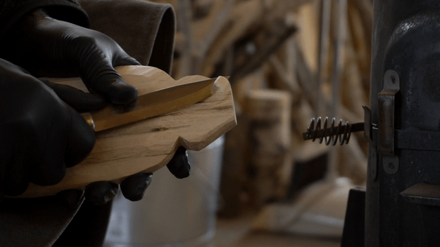 Worker carving wood precisely with a knife in workshop