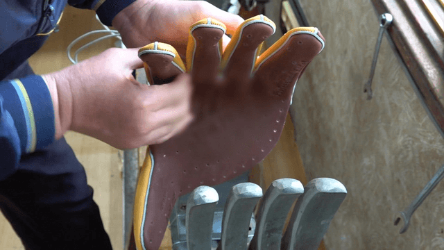 Worker inserting leather into glove shaping machine
