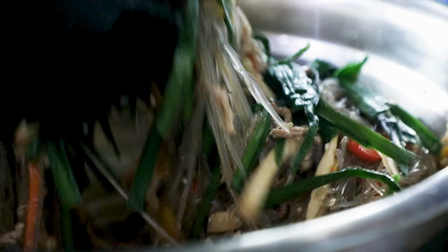 Mixing japchae with fresh vegetables