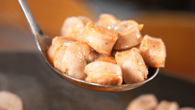 Ladle scooping hot stir-fried sausage