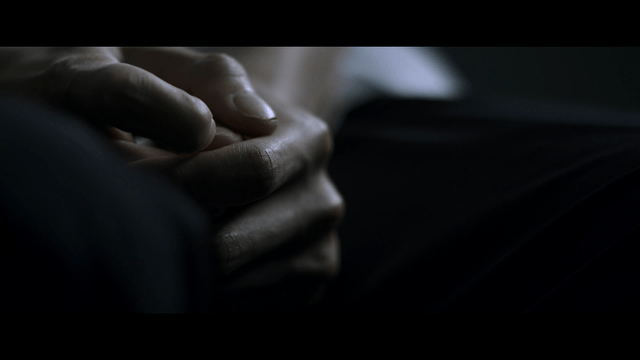 Anxious hands clasped between knees