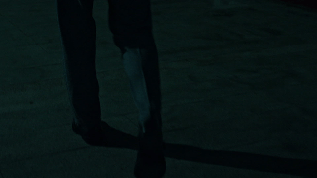 Man in a suit walking down a dark street at night