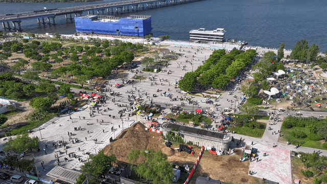 A bustling riverside park with tents and people