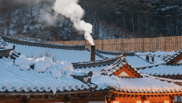 Snow-covered hanok with white smoke from chimney
