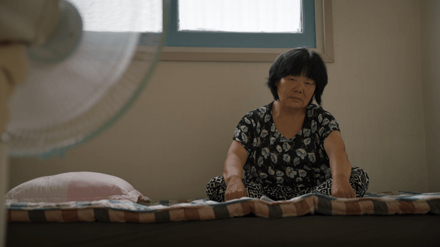 An elderly woman sitting on a bed indoors