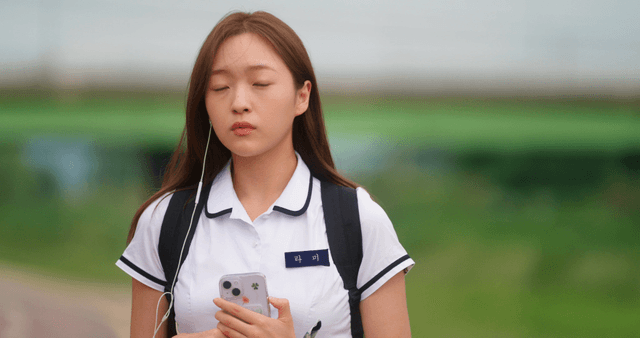 Schoolgirl holding a phone while wearing earphones