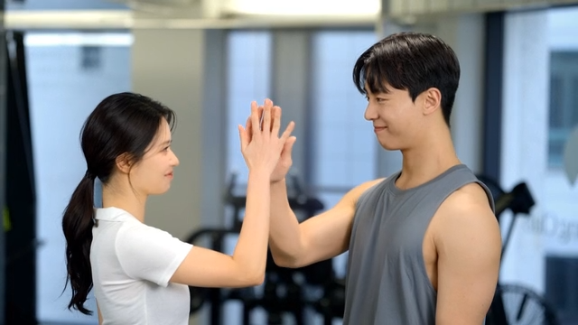 Couple high-fiving with a smile at the gym