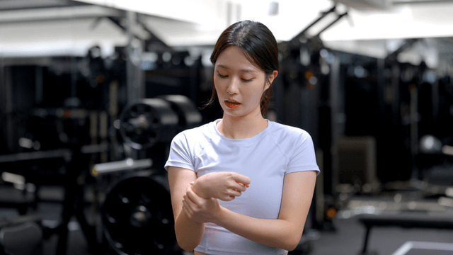 Young woman checking wrist injury at gym