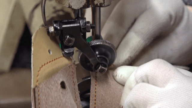 Sewing machine stitching leather in factory