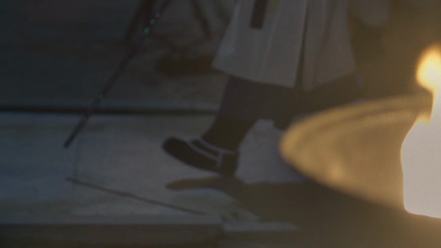 A person in a hanbok walking next to a burning flame