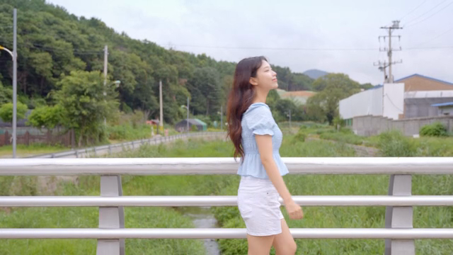 시골 다리 위를 걷는 여성