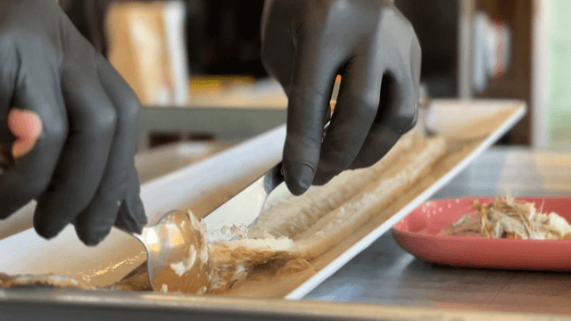 Gloved hands preparing fillets of grilled cutlassfish