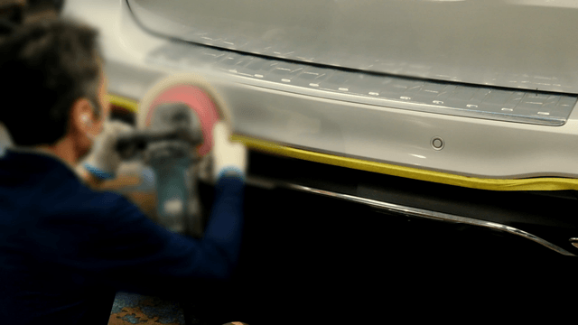 Worker polishing a car bumper