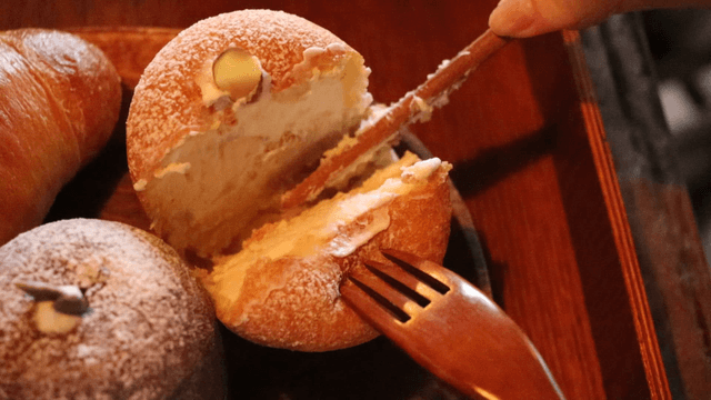 A person slicing a cream-filled pastry
