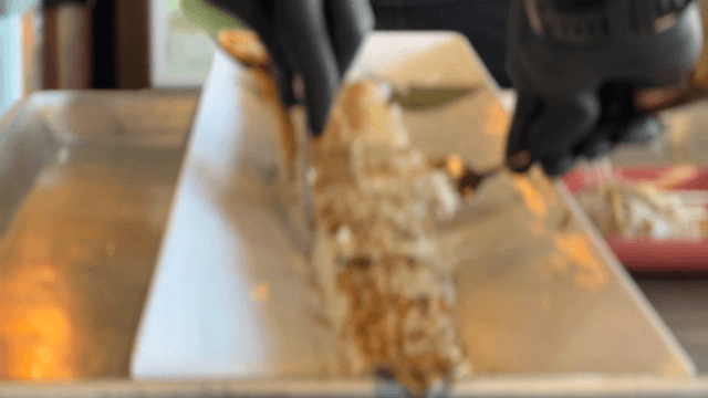 Gloved hands trimming boneless grilled cutlassfish