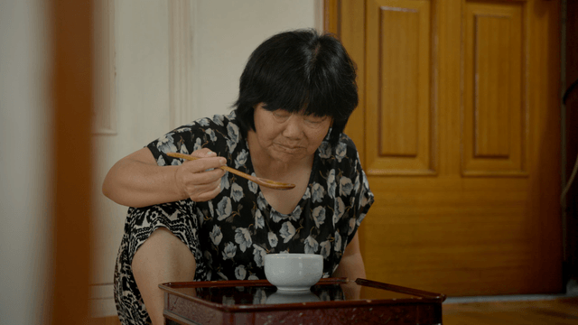 An elderly woman eating alone indoors