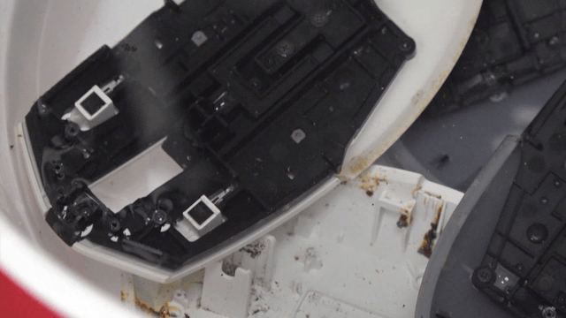 Plastic mouse parts submerged in cleaning solution