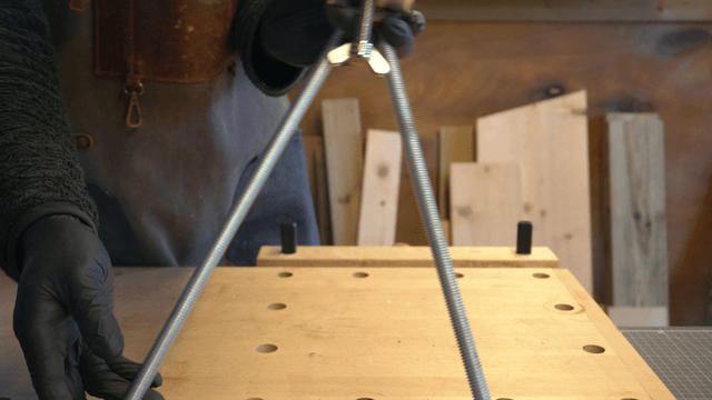 Artisan connecting metal rods and wooden pieces in workshop