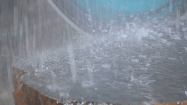 Fast-rotating industrial saw cutting a large stone with water spray