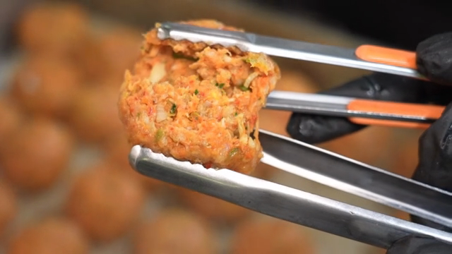 Slicing a kimchi rolling dumpling with tongs