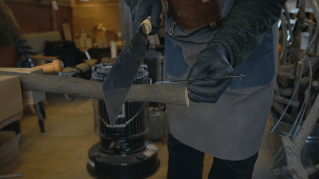 Woodcraft artisan cutting wood with a saw in workshop