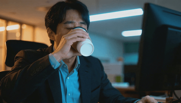 Tired office worker drinking coffee at desk