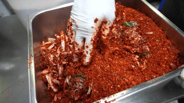 Kimchi ingredients being mixed on metal tray
