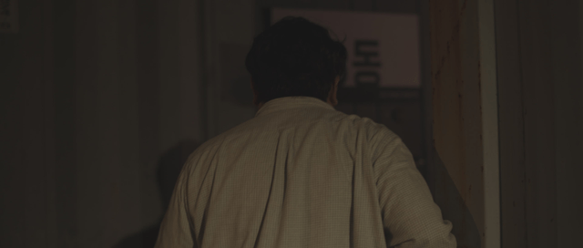 Man walking through a dimly lit hallway