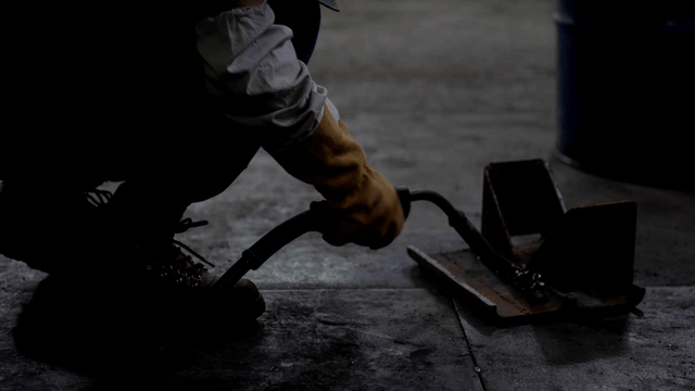 Worker welding metal pieces indoors