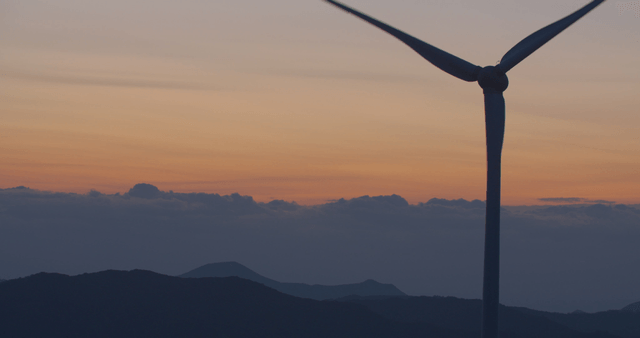 Wind turbine at sunset with mountains
